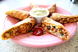 These tantalizing Taos Egg Rolls are the perfect beginning to your main course!  Filled with spicy grilled chilled chicken, red onions, corn, cilantro, cheese, avocado and roasted peppers, they