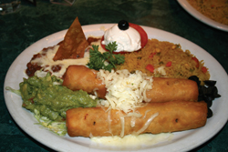 Chow down on <b>Chimichangas</b>! How can you resist two large flour tortillas filled with shredded beef or chicken and fried to a pastry flakiness and topped with sour cream and guacamole? It is even served with a bonus side of rice and refried bean