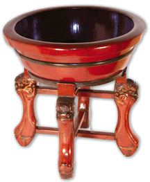 The red wooden baby bath and stand is decorated with gold fu dogs, protectors of the home and guardians of children