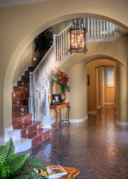 A bright-white staircase visually defines an entry filled with Spanish tile, brickwork and arches.